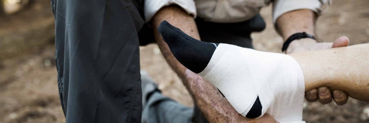 Elderly man bandaging his wife’s ankle