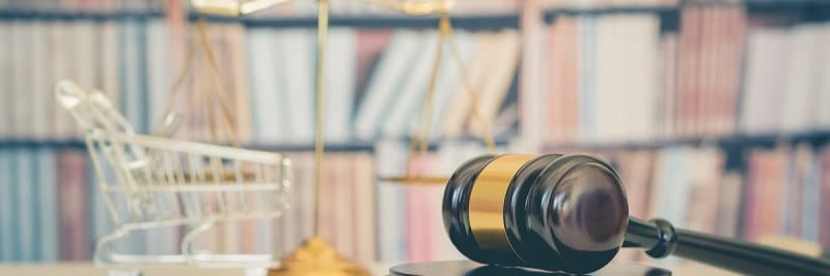 Consumer rights and consimer protection, business law concept : Wooden judge gavel, a shopping cart, a balanced scale of justice on a table, depicting the practice of safeguarding buyers of goods and services.